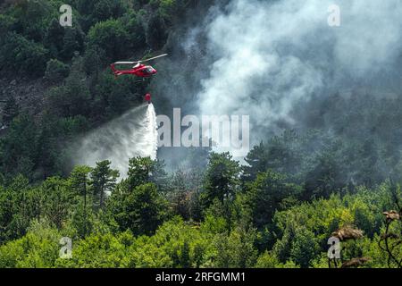 Dramatische Szene mit Flammen und Rauch von einem Waldbrand. Der Katastrophenschutz-Helikopter bekämpft die Flammen mit dem Wasser Monte Morrone, Maiella-Nationalpark Stockfoto