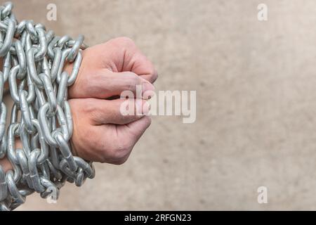 Die rauen Hände eines Arbeiters, eines weißen Mannes, sind in eine Kette gewickelt als Konzept von Sklaverei oder Gefängnis. Nahaufnahme der Hände eines Sklaven mit Stockfoto