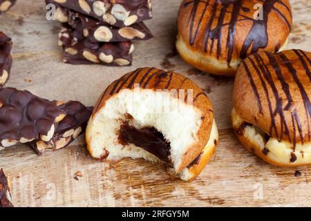 Köstlicher Donut bedeckt mit Schokoladenlinien und einer Füllung mit milchweicher Schokolade, ein Donut mit Schokoladenfüllung und in Schokolade Stockfoto
