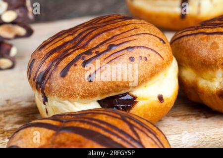 Köstlicher Donut bedeckt mit Schokoladenlinien und einer Füllung aus milchweicher Schokolade, Donut mit Schokoladenfüllung und in Schokolade Stockfoto