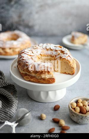 Klassisches französisches Pariser Brest in runder Form mit Mandeln und Haselnüssen auf einem weißen Teller. Stockfoto