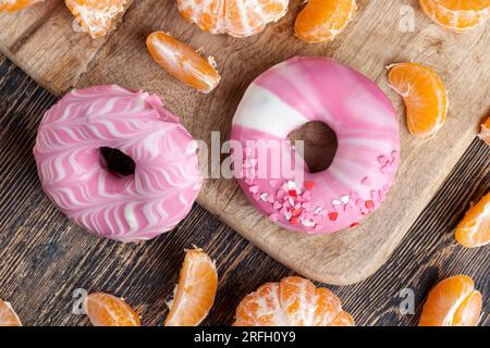 Köstlicher Donut bedeckt mit rosafarbener und weißer Schokolade mit Erdbeergeschmack, Donuts mit Beerenfüllung und Schokolade Stockfoto