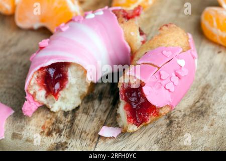 Köstlicher Donut bedeckt mit rosafarbener und weißer Schokolade mit Erdbeergeschmack, Donuts mit Beerenfüllung und Schokolade Stockfoto