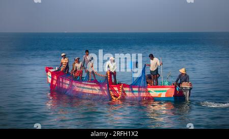 Indien, Kerala - 27. Dezember 2015: Indische Fischer ziehen die bemalte seine grafisch direkt in Boot 2. Netz lackiert in leuchtenden Farben, fliegende Seeschwalben, Holz Stockfoto