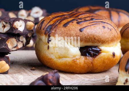 Köstlicher Donut bedeckt mit Schokoladenlinien und einer Füllung mit milchweicher Schokolade, ein Donut mit Schokoladenfüllung und in Schokolade Stockfoto