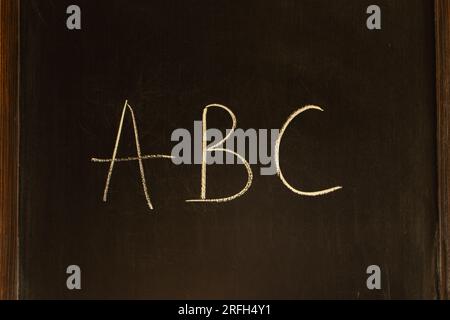 Kreidezeichnung an einer Tafel. Buchstaben ABC auf Holzbrett. Schultafel. Alphabet-Konzept. Handgeschriebener Text. Vorschulerziehung. Stockfoto