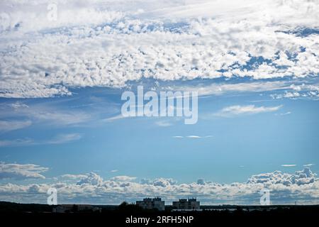Wunderschöner blauer Himmel mit stürmischen und welligen weißen Wolken vor Regen über der Stadt. Wetterwechsel Stockfoto