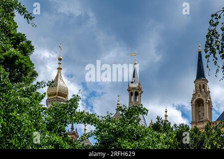 Schwerin, Mecklenburg-Vorpommern, Deutschland, 07 06 2023: Blick auf 3 Türme vom Schloss Schwerin vor blauem Himmel und von grünen Blättern umrahmt Stockfoto