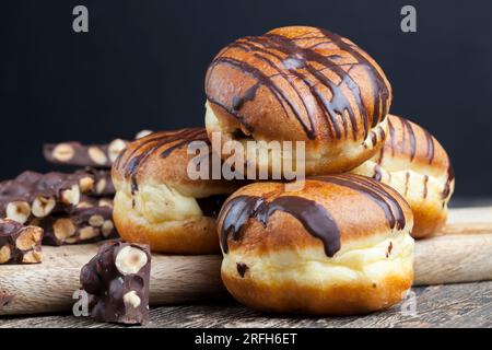Köstlicher Donut bedeckt mit Schokoladenlinien und einer Füllung mit milchweicher Schokolade, ein Donut mit Schokoladenfüllung und in Schokolade Stockfoto