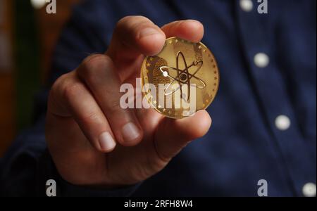 Cosmos ATOM Kryptowährung Goldmünze in Hand abstraktes Konzept Stockfoto