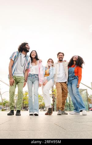 Vertikales Porträt von glücklichen jungen erwachsenen Freunden, die Spaß haben, lachen, spazieren gehen und miteinander reden. Gruppe sorgenfreier und vielfältiger Menschen, die am Wochenende oder in den Ferien Besichtigungen genießen. Freunde. Hochwertiges Foto Stockfoto