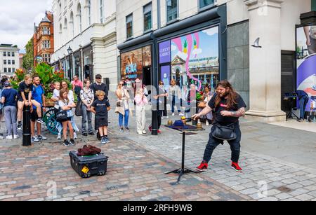 Der australische Straßenmagier Jason Maher tritt im Covent Garden im Londoner West End WC2 auf und unterhält eine Menge Stockfoto