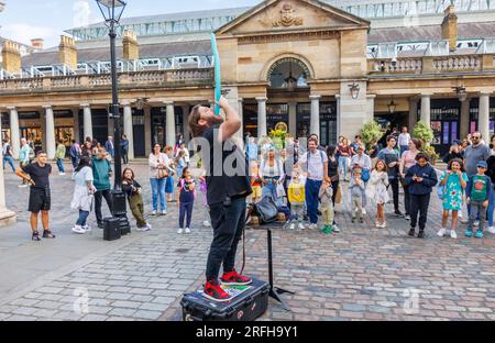 Der australische Straßenmagier Jason Maher Slowing a Balloon tritt im Covent Garden im Londoner West End WC2 auf und unterhält eine Menge Stockfoto