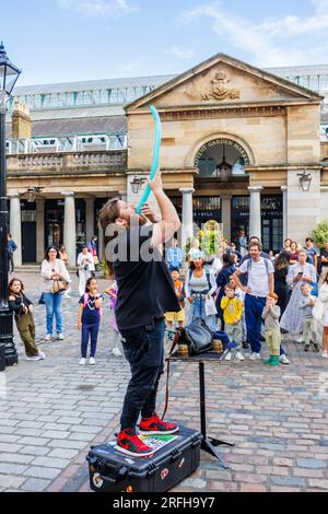 Der australische Straßenmagier Jason Maher Slowing a Balloon tritt im Covent Garden im Londoner West End WC2 auf und unterhält eine Menge Stockfoto