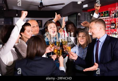 Internationale Gruppe von Geschäftsleuten, die mit Champagner toasten und sich auf der Büroparty im Nachtclub amüsieren Stockfoto