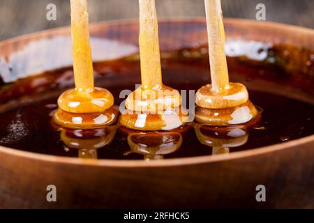 Löffel für Honig zusammen mit hochwertigem Bienenhonig, einem alten Tisch, auf dem ein gesunder und süßer Bienenhonig steht, und einem speziellen Holzlöffel von Stockfoto