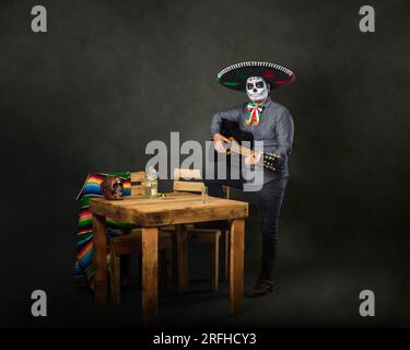 Catrin trägt einen Mariachi-Hut und spielt Gitarre in einer Bar. Der Tag der Totenfeier. Stockfoto