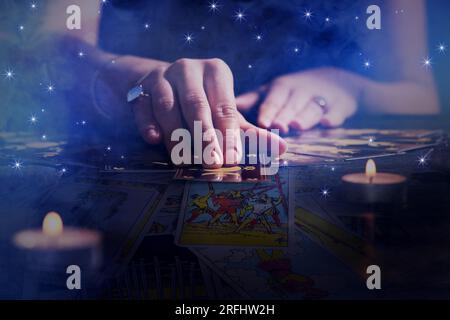 Wahrsagerin, die die Zukunft vorhersagt, mit Tarotkarten am Tisch in der Dunkelheit, Nahaufnahme. Doppelte Belichtung Stockfoto