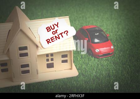 Hausmodell mit Karte Kaufen oder mieten Sie in der Nähe eines Spielzeugautos auf grünem Gras Stockfoto