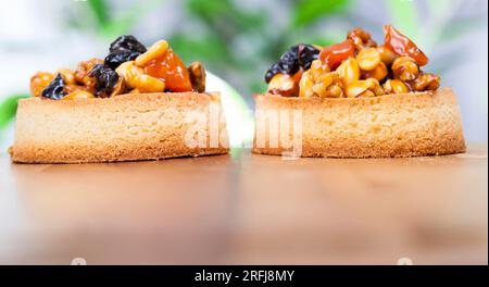 Weizentörtchen mit süßer Füllung, knusprige Törtchen mit Haselnüssen, Erdnüssen und anderen Zutaten, Weizenteig Törtchen mit Nüssen und getrockneten Früchten in Crea Stockfoto