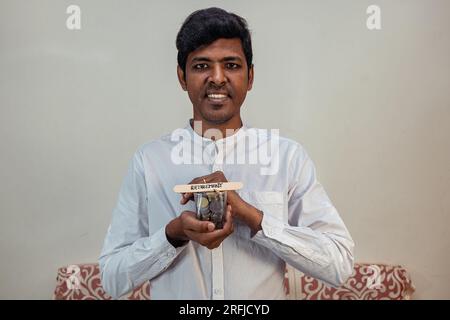 Ein Mann hält ein Glas indische Rupien-Münzen, mit dem Wort "Rétirement" auf einem Stock Stockfoto