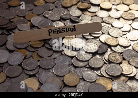 Ein Nahfoto von indischen Rupien-Münzen, die auf einem Tisch verteilt sind. Die Münzen sind kreisförmig angeordnet, und das Wort "Rente" steht auf einem Stab Stockfoto