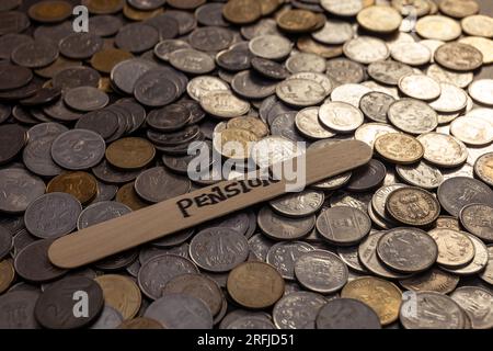 Dieses Aktienbild zeigt einen Haufen indischer Rupien-Münzen auf einem Tisch. Das Wort "Rente" steht auf einem Stab auf dem Tisch vor den Münzen. Stockfoto