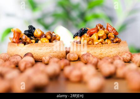 Weizentörtchen mit süßer Füllung, knusprige Törtchen mit Haselnüssen, Erdnüssen und anderen Zutaten, Weizenteig Törtchen mit Nüssen und getrockneten Früchten in Crea Stockfoto