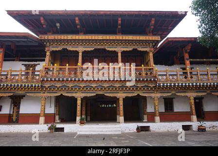 Farbenfrohe historische Holzarchitektur im Punakha Dzong in Bhutan. Ein Balkon mit quadratischem überhängendem Dach befindet sich auf einer Reihe von geschnitzten gemalten Säulen Stockfoto