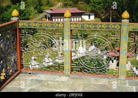Dekoratives Gitter aus Eisenarbeiten, das das buddhistische Dharmachakra oder Dharmarad darstellt, das in einem Geländer auf dem Khamsum Yulley Namgyal Chorten, Bhutan, angebracht ist Stockfoto