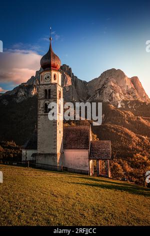 Seis am Schlern, Italien - St. Valentin Kirche und der berühmte Berg Sciliar in den italienischen Dolomiten mit blauem Himmel und warmem Sonnenlicht in Südtirol auf einem au Stockfoto