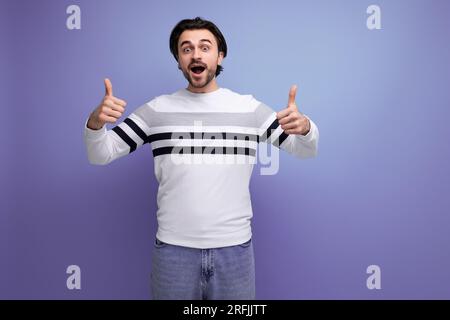 Der süße kaukasische brünette junge Mann zeigt das Stockfoto