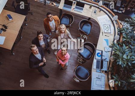 Gruppe von Kollegen, die im Büro stehen und vor die Kamera schauen. Arbeitsplatz- und Kooperationskonzept Stockfoto