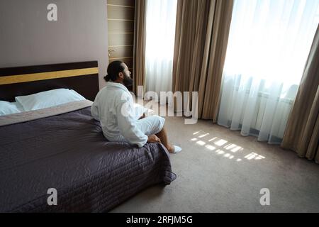 Hotelgäste mittleren Alters sitzen auf einem großen Bett in einem gemütlichen Schlafzimmer Stockfoto