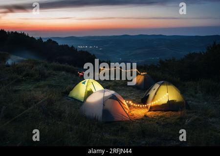 Am Abend beim Camping in den Bergen. Beleuchtete Zelte in einem malerischen Tal. Stockfoto