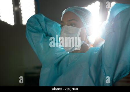Birassische Chirurgin mit Operationskittel und Gesichtsmaske im Operationssaal des Krankenhauses Stockfoto