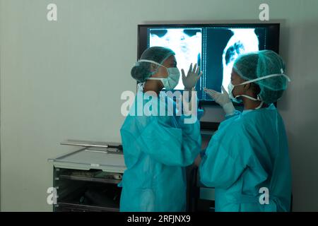 Vielfältige Chirurgen betrachten Röntgenaufnahmen im Operationssaal des Krankenhauses Stockfoto