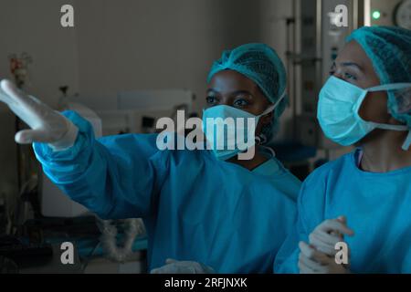 Vielfältige Chirurgen betrachten Röntgenaufnahmen im Operationssaal des Krankenhauses Stockfoto