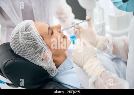 Frau in der Zahnarztpraxis erhält eine Injektion mit Schmerzmittel Stockfoto