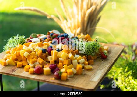 Gehen Sie an Bord mit verschiedenen Käsesorten und Früchten, die im Sommer für ein Buffet im Hof zubereitet werden Stockfoto