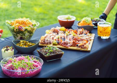 Der Kellner stellt das Gericht mit Vorspeisen für ein Buffet im Garten auf den Tisch Stockfoto