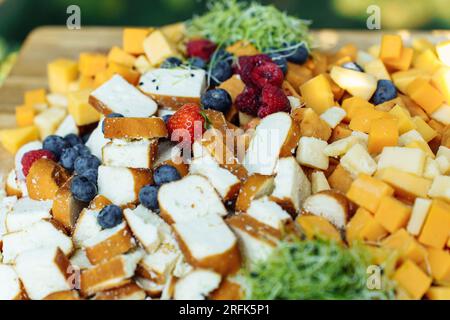 Gehen Sie an Bord mit Käse, Brot und Beeren für ein festliches Buffet im Sommer im Hof Stockfoto