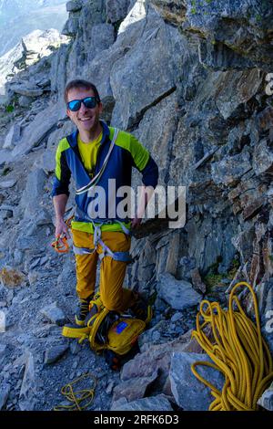 Ein lächelnder Bergsteiger bereitet den Aufstieg zum Pizzo Nero in den Schweizer Alpen vor Stockfoto