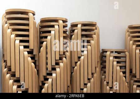 Gestapelte Holzhocker aus gebogenem Sperrholz vor einer weißen Wand Stockfoto