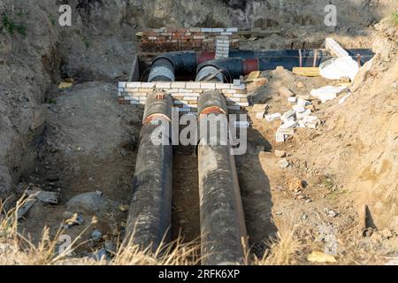 Unterirdische Grabenverlegung neuer Rohre im städtischen Wasser- und Heiznetz. Moderne Abwasserrohre aus Kunststoff, die nicht verrotten können. Stockfoto