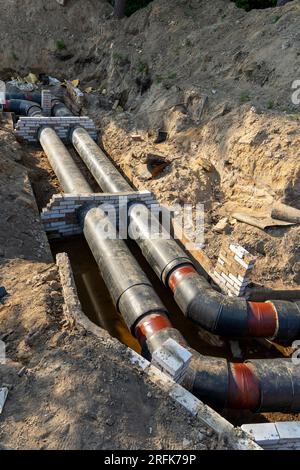 Unterirdische Grabenverlegung neuer Rohre im städtischen Wasser- und Heiznetz. Moderne Abwasserrohre aus Kunststoff, die nicht verrotten können. Stockfoto