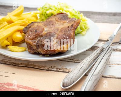 Schweinesteak mit Pommes Frites und Kohlsalat auf weißem Teller Stockfoto