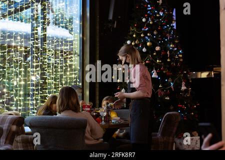 22.01.2022 St. petersburg, Russland. Leute, die an weihnachtsfeiertagen im Restaurant bestellen. Kellnerin trägt schwarze Gesichtsmaske und schreibt auf Nein Stockfoto