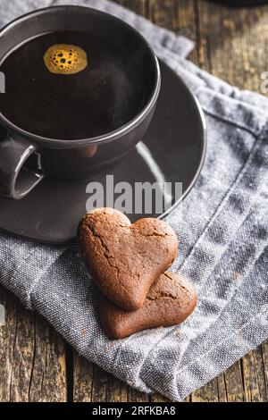 Herzförmige Kekse und Kaffeetasse auf dem Holztisch. Stockfoto