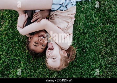 Kinder, die im Gras liegen, sind albern Stockfoto